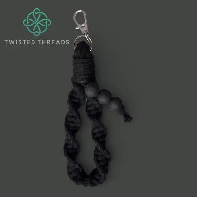 Black braided keychain with a metal clasp on a dark gray background