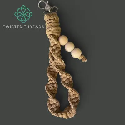 Brown braided keychain with three beads on a dark gray background