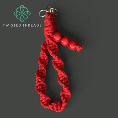 Red braided keychain with beads on a dark gray background