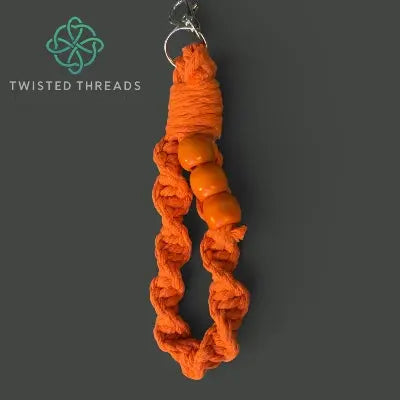 Orange braided keychain with beads on a dark gray background