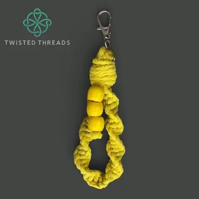 Yellow colour drenched wristlet keychain with beads on a gray background