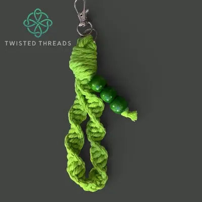 Green braided keychain with beads on a dark gray background