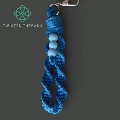 Blue braided keychain with white beads on a gray background