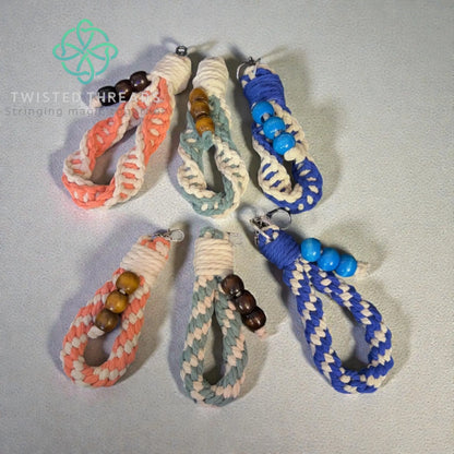 Set of braided keychains with beads on a light gray background