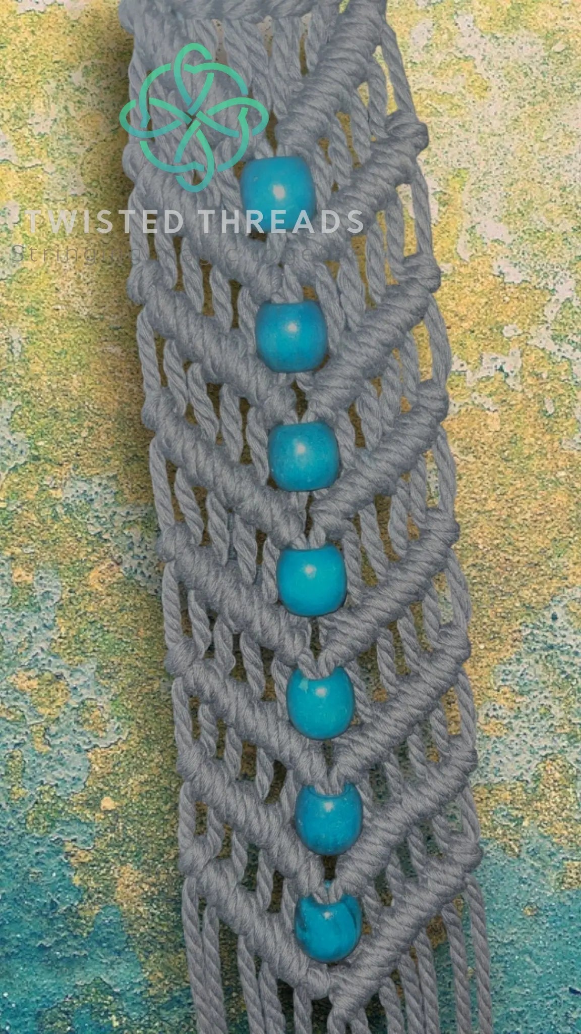 White V-shaped macrame plant hanger with beads by Twisted Threads Au, designed for hanging small to medium plants.